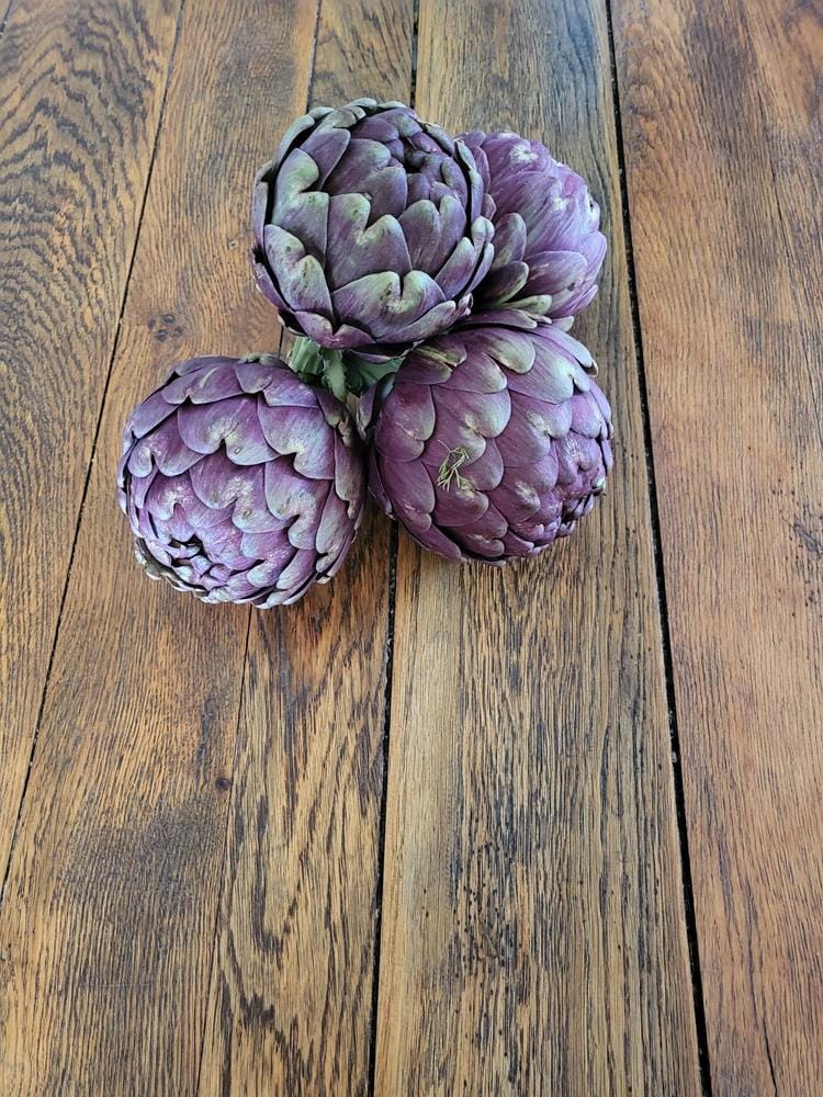 Drei frische Artischocken auf Holztisch